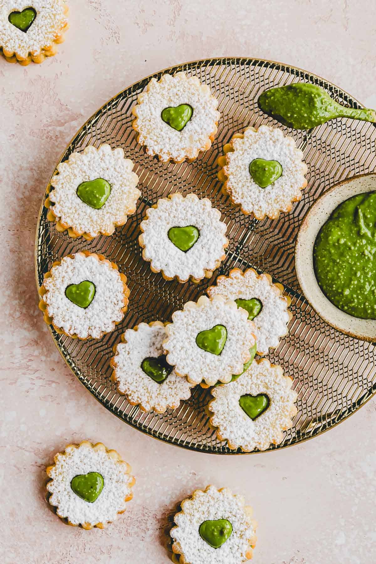 Plätzchen mit Pistaziencreme auf einem goldenen auskühlgitter präsentiert