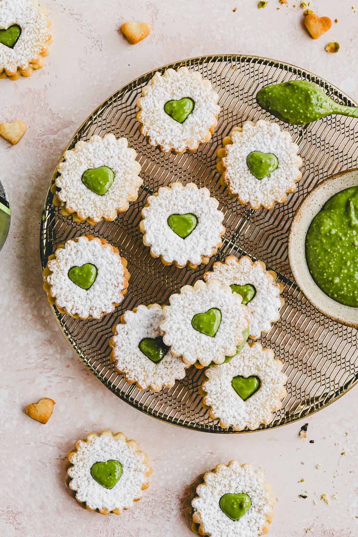 Plätzchen mit Pistaziencreme auf einem goldenen auskühlgitter präsentiert