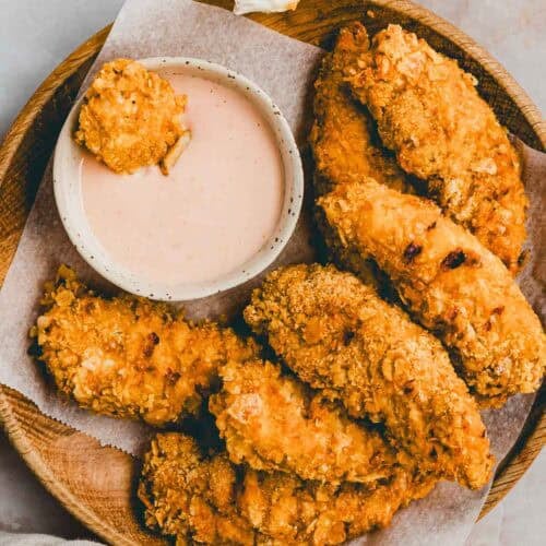 chicken nuggets im airfryer auf einem holzteller mit dipping sauce serviert