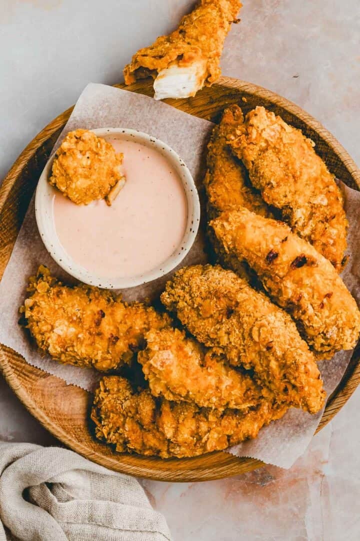 chicken nuggets im airfryer auf einem holzteller mit dipping sauce serviert
