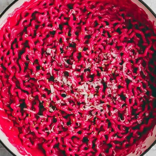 pink pasta (rote bete pasta) in einer servierpfanne mit parmesan dekoriert