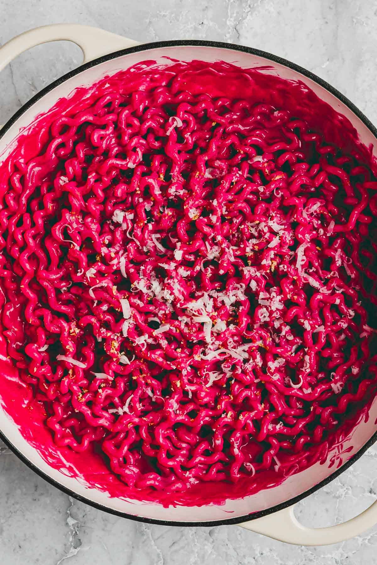 pink pasta (rote bete pasta) in einer servierpfanne mit parmesan dekoriert
