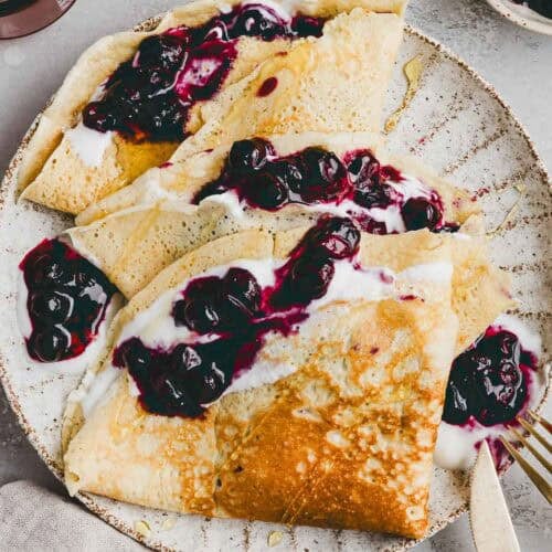 high protein crepes served on a plate with blueberries and yogurt