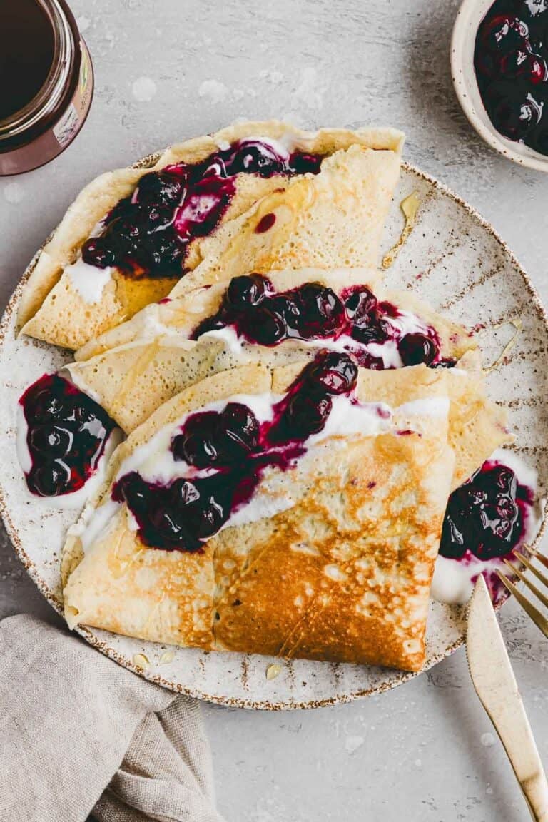 high protein crepes served on a plate with blueberries and yogurt