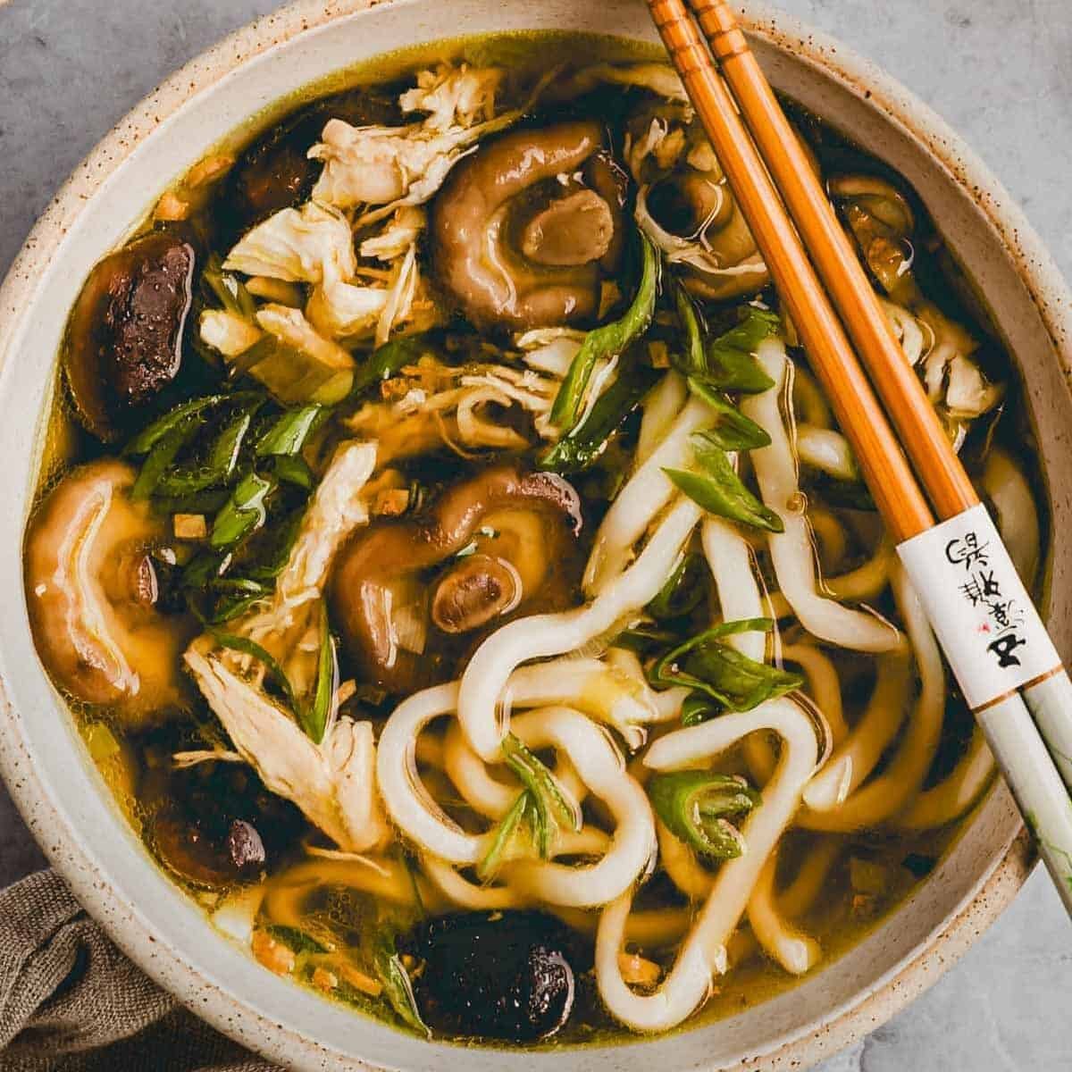 proteinreiche udon suppe mit hähnchen und shiitake in einer schüssel serviert