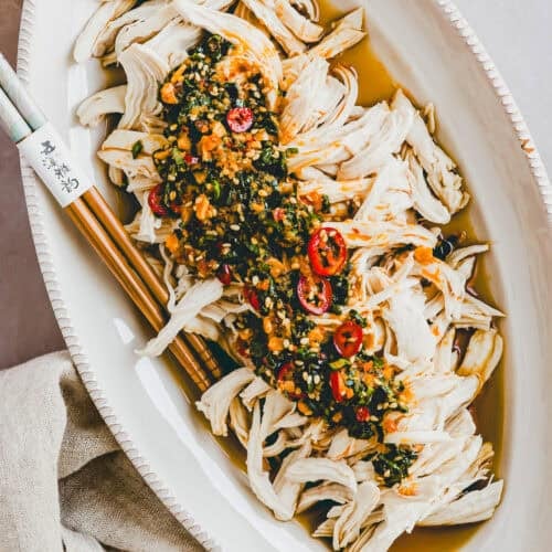 Pochiertes Hähnchen mit pikanter Chili-Sauce in einer weissen servierschale