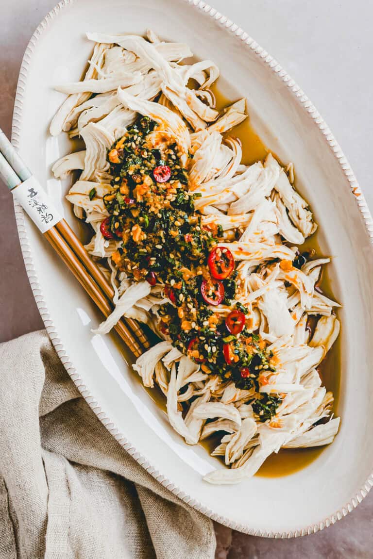 Pochiertes Hähnchen mit pikanter Chili-Sauce in einer weissen servierschale