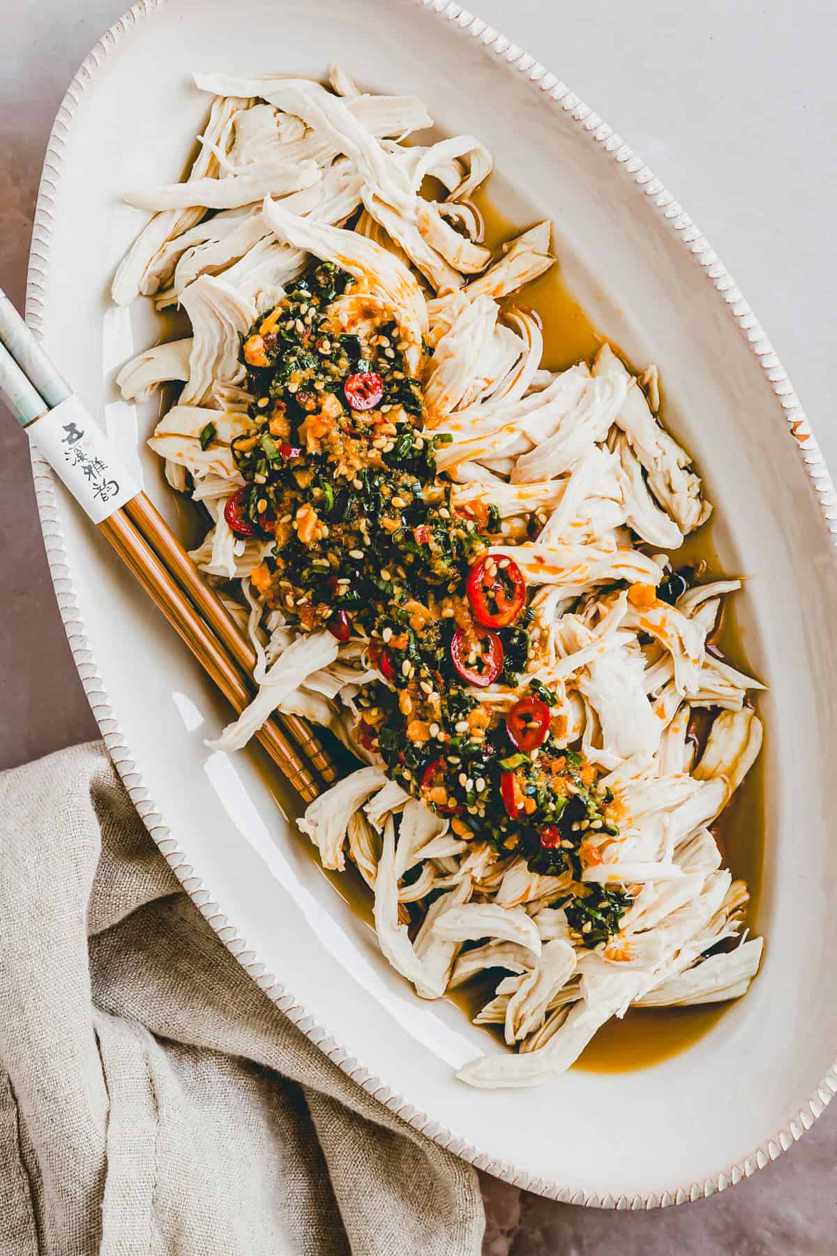 Pochiertes Hähnchen mit pikanter Chili-Sauce in einer weissen servierschale